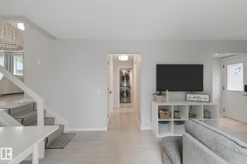 Light wood-finish flooring, white painted walls, and a staircase with a striped runner - 5 Labelle Crescent, St. Albert, AB 