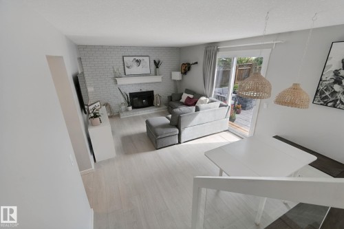 Light wood-finish flooring, white painted brick fireplace with mantel, white ceiling, white walls, sliding glass door to exterior - 5 Labelle Crescent, St. Albert, AB 