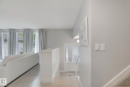 Entryway with a light wood-finish flooring, white paneled walls, and a split-level design featuring a carpeted staircase - 5 Labelle Crescent, St. Albert, AB 