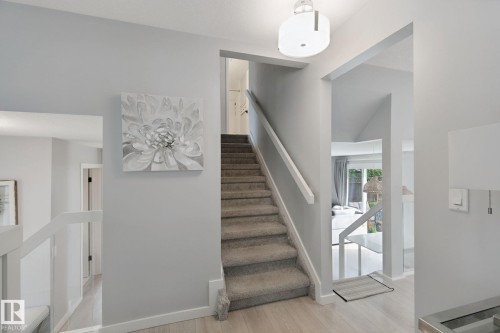 Wood-finish flooring, carpeted stairs with painted handrail, and a contemporary ceiling light fixture - 5 Labelle Crescent, St. Albert, AB 