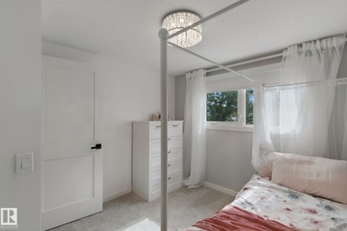 White flat-panel interior door with matte black hardware, dual-pane window, and a multi-tiered crystal chandelier - 5 Labelle Crescent, St. Albert, AB 