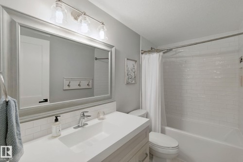 Contemporary bathroom featuring a large framed mirror, vanity with an integrated sink, polished chrome faucet, and a subway tile shower surround - 5 Labelle Crescent, St. Albert, AB 