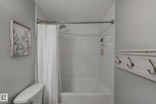 Bathtub with white subway tile surround, built-in shower niche, and ceiling-mounted shower head - 5 Labelle Crescent, St. Albert, AB 