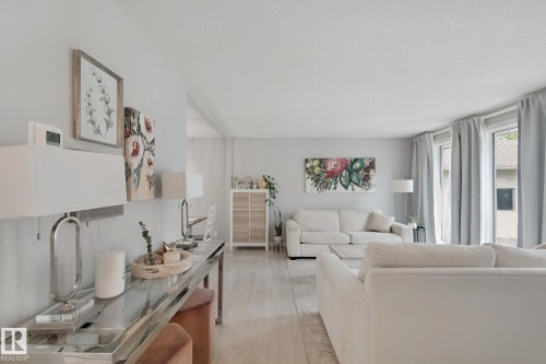 Light wood-finish flooring throughout, multiple large windows with drapes, and recessed wall paneling - 5 Labelle Crescent, St. Albert, AB 
