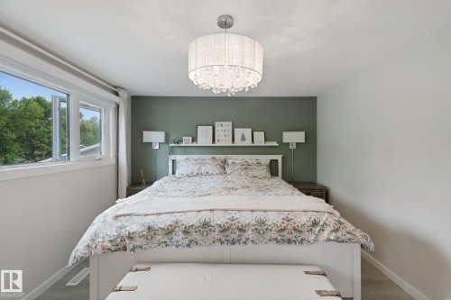 White frame window, feature wall in a muted tone, flush-mount chandelier with crystal accents, built-in shelving, and wood-finish flooring - 5 Labelle Crescent, St. Albert, AB 