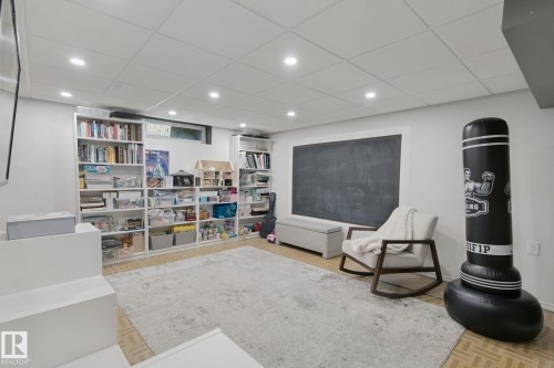 Recessed lighting illuminating a spacious room with built-in shelving, wood-finish flooring, and a large chalkboard wall - 5 Labelle Crescent, St. Albert, AB 