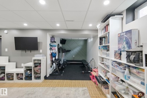 Recessed lighting, wood-finish flooring, built-in shelving, and a dedicated exercise area with textured accent wall - 5 Labelle Crescent, St. Albert, AB 