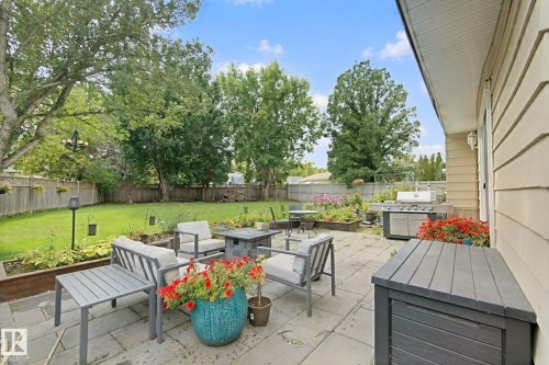 Expansive backyard featuring a stone paver patio, a fenced perimeter, and mature trees - 5 Labelle Crescent, St. Albert, AB 