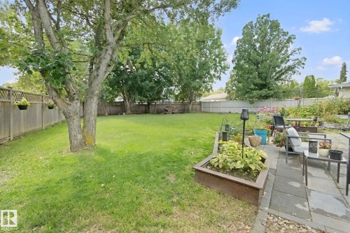 Expansive backyard featuring a manicured lawn, established trees, a paver patio, and a raised planter bed - 5 Labelle Crescent, St. Albert, AB 