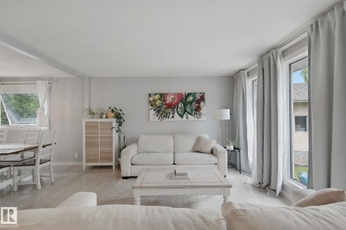 Bright living space with light wood-finish flooring, featuring multiple windows, and a built-in storage unit - 5 Labelle Crescent, St. Albert, AB 