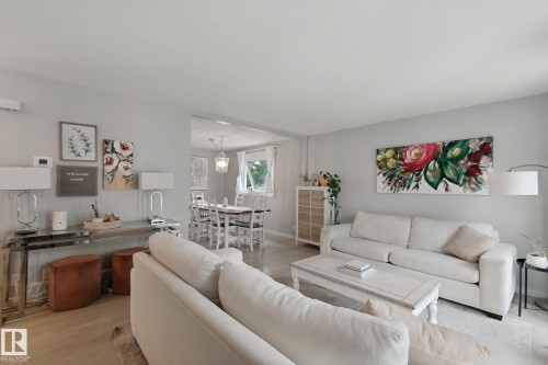 Light wood-finish flooring throughout, bright walls, and a dining area with a chandelier - 5 Labelle Crescent, St. Albert, AB 