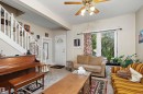 Living area with carpet flooring, a white paneled entry door with an arched transom, a double window, and a ceiling fan - 10816 92 Street Nw, Edmonton, AB 