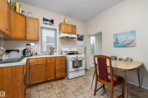 Kitchen featuring wood cabinetry, white countertops, a white gas range, and neutral-toned floor tiling - 10816 92 Street Nw, Edmonton, AB 