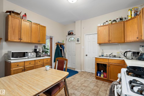 Kitchen featuring wood cabinetry, laminate countertops, and patterned floor tile - 10816 92 Street Nw, Edmonton, AB 