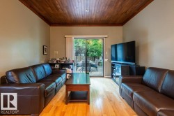 Family room area featuring wood-finish flooring, a wood plank ceiling, and direct access to an outdoor deck through sliding glass doors - 