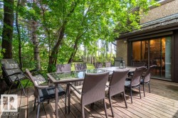Expansive wood-finish deck with mature trees, offering direct access to the interior via sliding glass doors - 