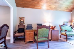 Sloped wood-paneled ceiling above a room with wood-finish flooring and light-toned walls - 