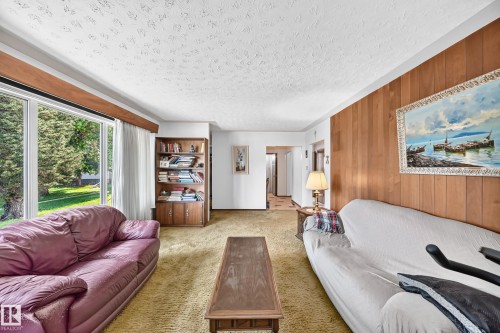 Living area featuring a large picture window, textured ceiling, and wood-paneled accent wall - 15703 84 Avenue Nw, Edmonton, AB - Indoor Photo Showing Living Room