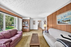 Living area featuring a large picture window, textured ceiling, and wood-paneled accent wall - 