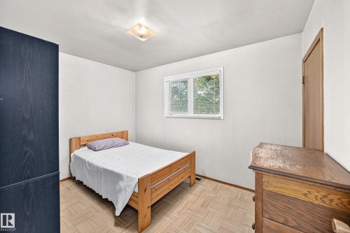 Bedroom featuring a window with blinds, wood-finish flooring, a flush-mount ceiling light, and a solid wood door - 15703 84 Avenue Nw, Edmonton, AB - Indoor Photo Showing Bedroom