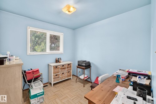 Room featuring light blue walls, wood-finish flooring, a white-framed window with blinds, and a flush mount ceiling light fixture - 15703 84 Avenue Nw, Edmonton, AB - Indoor
