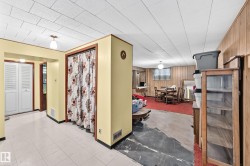 Basement room featuring a dropped ceiling, wood-paneled walls, and a recessed window - 