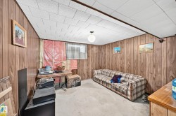 Basement space featuring wood paneling, a drop ceiling, and exposed insulation - 