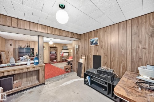 Versatile room featuring wood paneling throughout, a white acoustic tile ceiling, and a built-in wood-finish bar - 15703 84 Avenue Nw, Edmonton, AB - Indoor Photo Showing Other Room