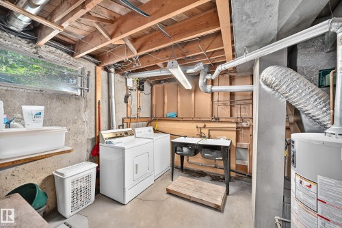 Dedicated laundry area featuring a side-by-side washer and dryer, double basin utility sink, and a water heater - 15703 84 Avenue Nw, Edmonton, AB - Indoor