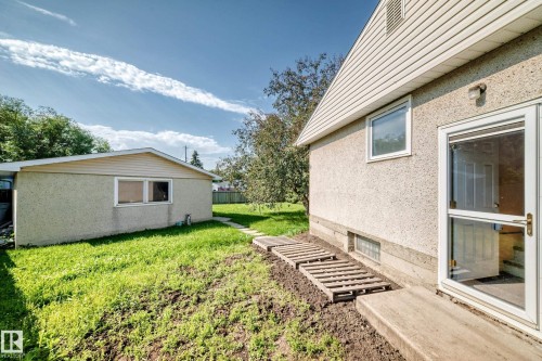Rear exterior with a concrete patio, white storm door, and stucco finish - 15703 84 Avenue Nw, Edmonton, AB - Outdoor With Exterior