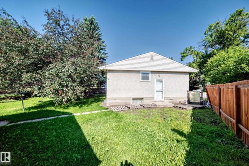 Rear exterior featuring a white gabled roof, stucco siding, and a white entry door - 15703 84 Avenue Nw, Edmonton, AB - Outdoor