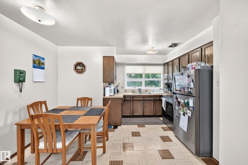 Kitchen featuring wood-finish cabinetry, a stainless steel refrigerator, and a window above the sink - 15703 84 Avenue Nw, Edmonton, AB - Indoor Photo Showing Other Room