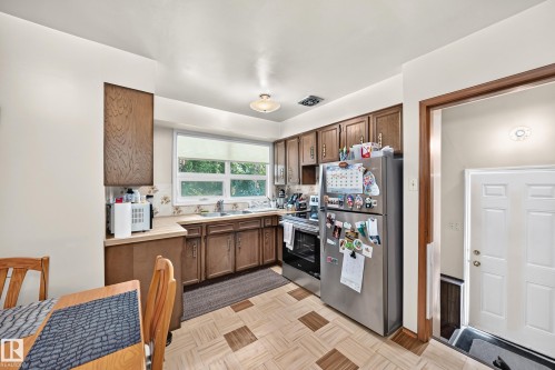 Kitchen featuring wood-finish cabinetry, a double basin sink, and a stainless steel refrigerator - 15703 84 Avenue Nw, Edmonton, AB - Indoor Photo Showing Kitchen With Double Sink