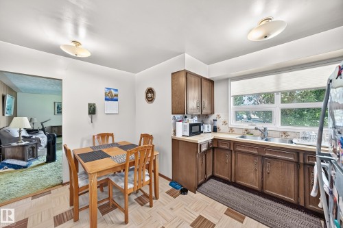 Eat-in kitchen featuring wood-finish cabinetry, a double basin sink, and ample natural light from a large window - 15703 84 Avenue Nw, Edmonton, AB - Indoor
