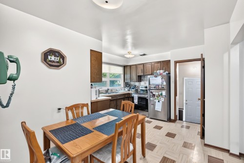 Kitchen featuring wood cabinetry, stainless steel appliances, and a window above the sink - 15703 84 Avenue Nw, Edmonton, AB - Indoor Photo Showing Dining Room
