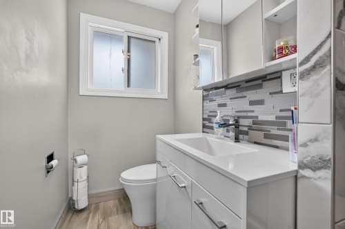 White vanity with an integrated rectangular sink, sleek cabinetry, and a contemporary tile backsplash - 13512 111 Street Nw, Edmonton, AB 
