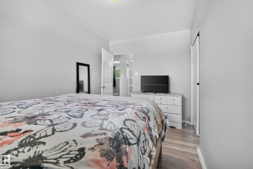 Wood-finish flooring with light gray walls, a white paneled door, and a white dresser - 13512 111 Street Nw, Edmonton, AB 