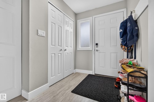 Entryway featuring light wood-finish flooring, a paneled door with frosted sidelite, and bi-fold closet doors - 13512 111 Street Nw, Edmonton, AB 