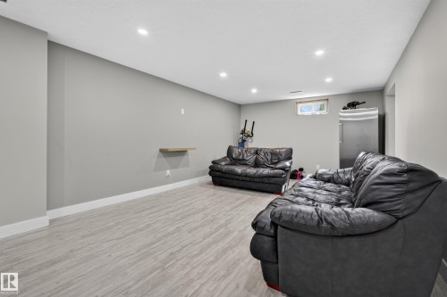 Recessed lighting, light wood-finish flooring, a stainless-steel refrigerator, and a window provide a bright, functional space - 13512 111 Street Nw, Edmonton, AB 