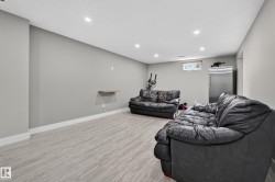 Recessed lighting, light wood-finish flooring, a stainless-steel refrigerator, and a window provide a bright, functional space - 