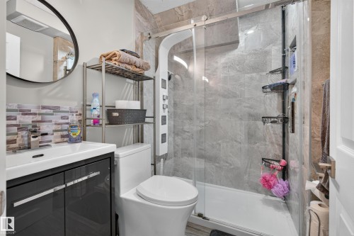 Walk-in shower with a glass enclosure and built-in panel, modern vanity with a vessel sink, and an accent tile backsplash - 13512 111 Street Nw, Edmonton, AB 