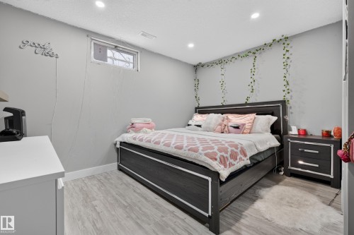 Recessed ceiling lighting, light wood-finish flooring, a fixed window with security bars, and a built-in wall niche - 13512 111 Street Nw, Edmonton, AB 