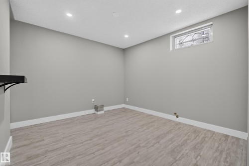 Recessed lighting, wood-finish flooring, light gray walls, white trim, and a window with security bars - 13512 111 Street Nw, Edmonton, AB 