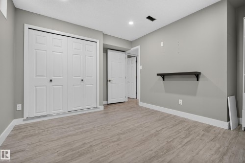Wood-finish flooring with white baseboards, recessed lighting, and a built-in wall shelf - 13512 111 Street Nw, Edmonton, AB 