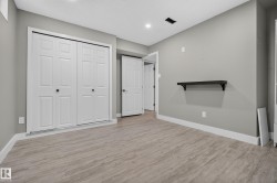 Wood-finish flooring with white baseboards, recessed lighting, and a built-in wall shelf - 