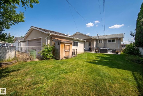 Expansive backyard with a manicured lawn, a detached storage shed, and a paved patio area - 13512 111 Street Nw, Edmonton, AB 