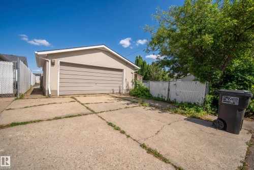 Detached garage featuring a horizontal panel door, stucco exterior, and concrete drive - 13512 111 Street Nw, Edmonton, AB 