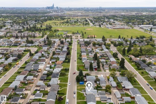 Aerial perspective showcasing residential streets, mature trees, open green spaces, and distant city skyline - 13512 111 Street Nw, Edmonton, AB 
