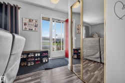 Wood-finish flooring, full-length mirror, light fixture, and a red entry door - 