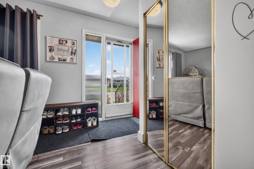 Wood-finish flooring, full-length mirror, light fixture, and a red entry door - 13512 111 Street Nw, Edmonton, AB 